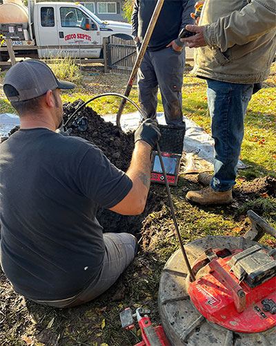 three men inspecting septic system in ground